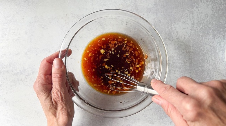 Whisking honey, lime, habanero marinade in glass bowl