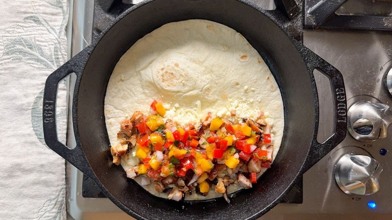 Peach pico de gallo, chopped chicken, cheese and flour tortilla in cast iron skillet