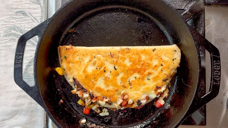 Quesadilla cooking in cast iron skillet on stovetop