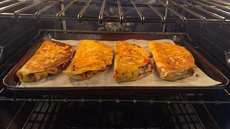 Cooked quesadillas on parchment-lined baking sheet in oven