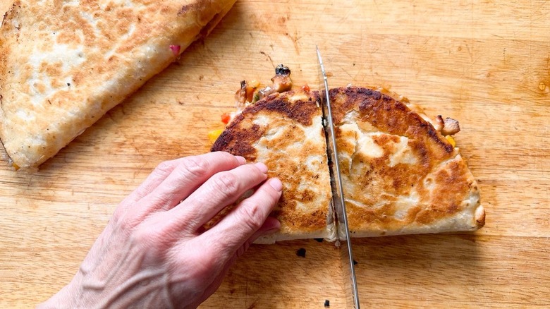 Cutting a quesadilla on a cutting board with a knife