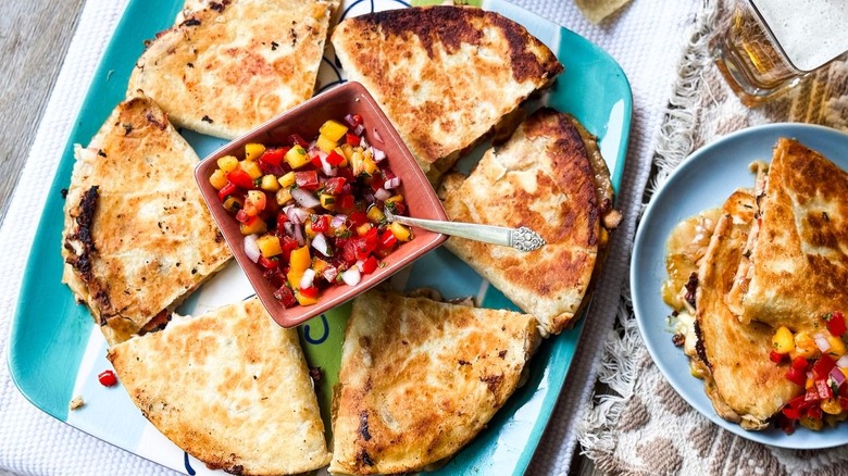 Sweet and spicy peach chicken quesadillas on serving platter with peach pico de gallo