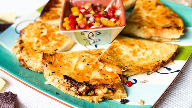 Sweet and spicy peach chicken quesadillas on serving platter with peach pico de gallo