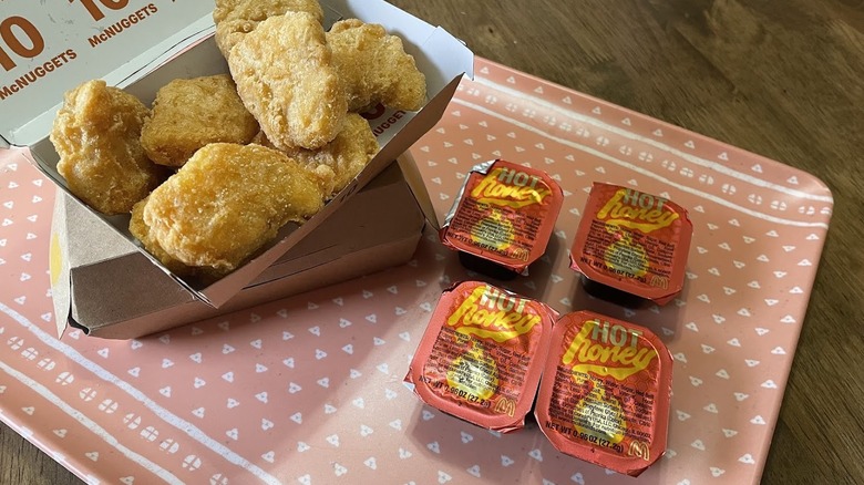 Chicken McNuggets with four Hot Honey Sauce packets on a tray.