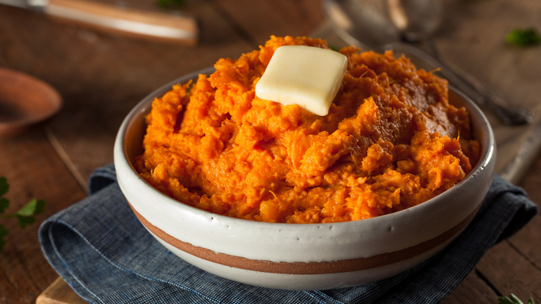 homemade mashed sweet potatoes topped with butter in a bowl.
