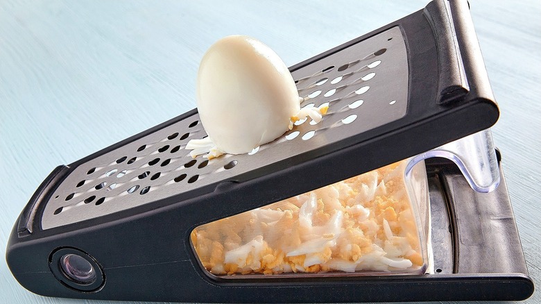 Part of a hard-boiled egg against the sharp side of a box grater