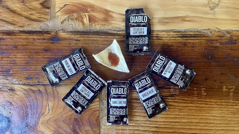 Packets of Taco Bell Diablo Sauce with a dollop on a tortilla chip
