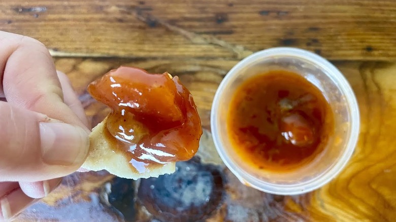 Hand holding tortilla chip dipped in Taco Bell Mexican Pizza Sauce