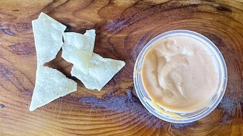Tortilla chips next to a ramekin of Taco Bell Creamy Jalapeño Sauce