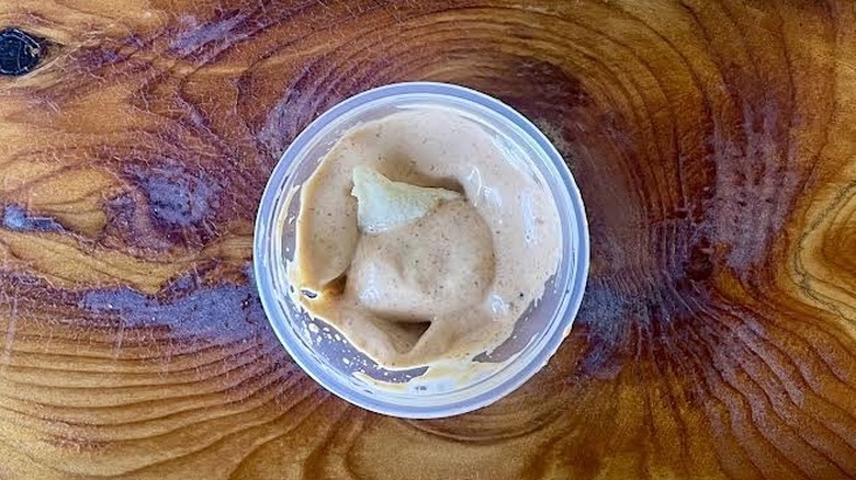 Small tortilla chip in a ramekin of Taco Bell Chipotle Sauce