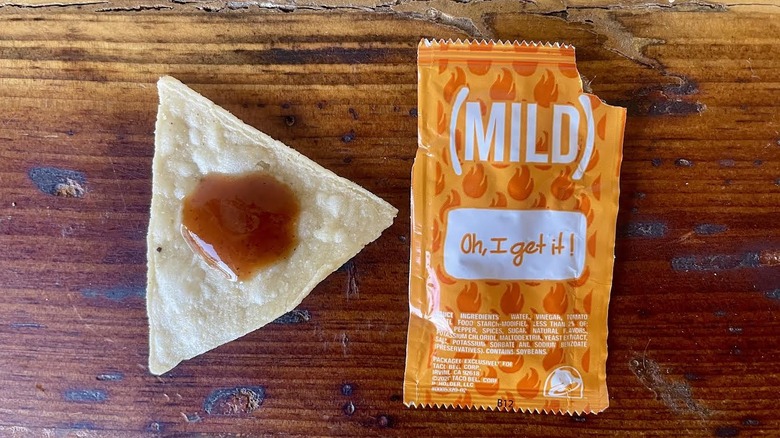 Taco Bell Mild Sauce Packet with some sauce on a tortilla chip