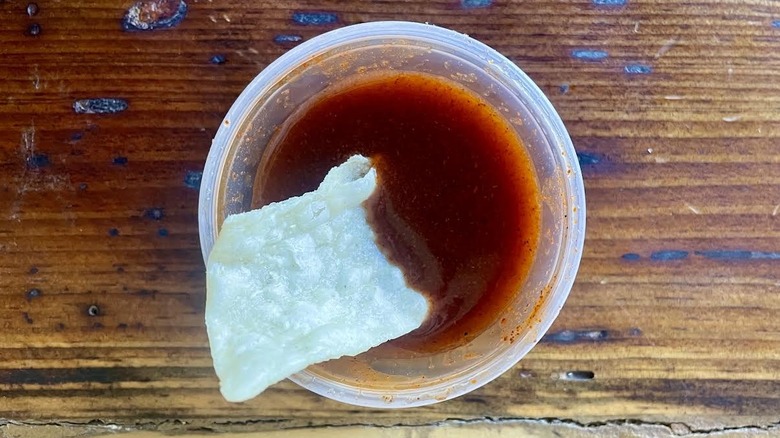 Tortilla chip in ramekin of Taco Bell Red Sauce