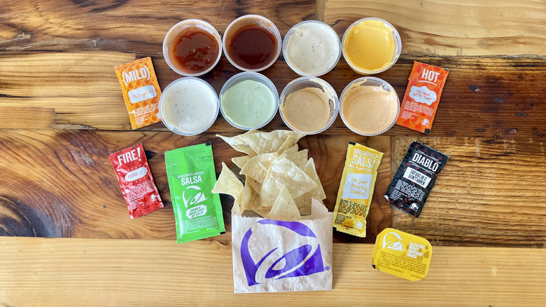 Overhead view of every Taco Bell sauce with a small bag of tortilla chips