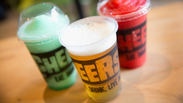 Three Taco Bell Cantina drinks including a beer and two Twisted Freeze drinks with the word Cheers written across each of the cups