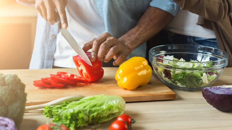 a person cutting bell peppers for a salad