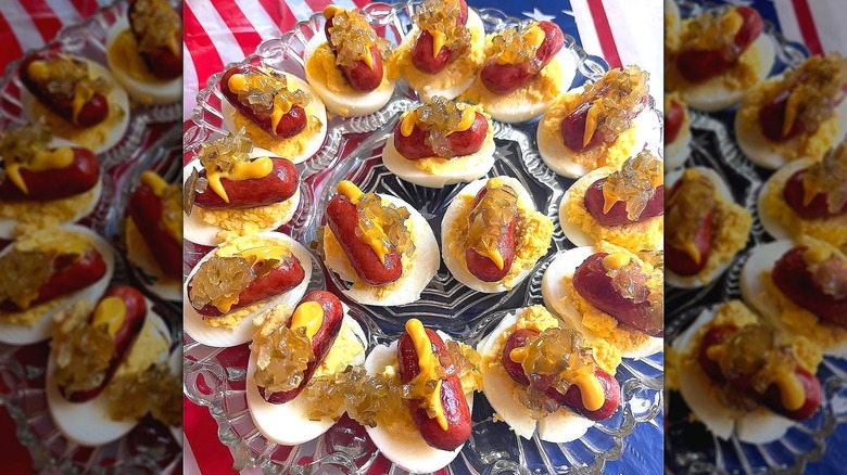 Hot dog deviled eggs on a clear serving platter over an American flag