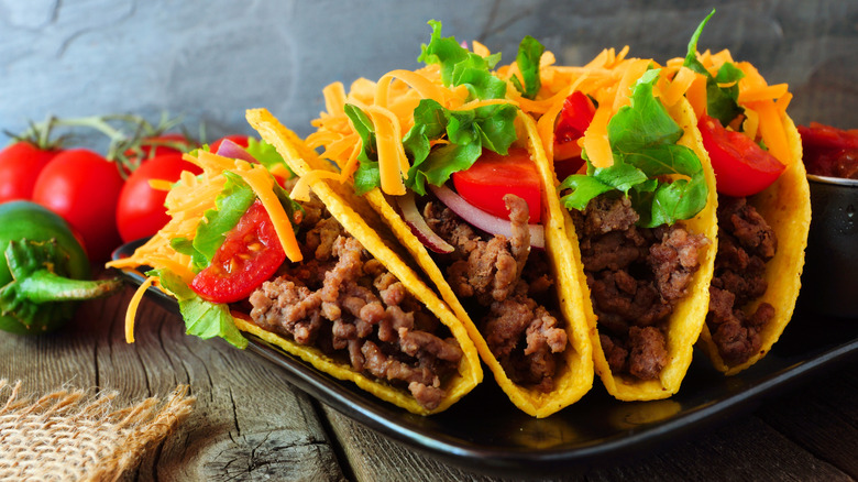 Four hard-shell ground beef tacos on a plate.