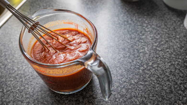 Stirring enchilada sauce in a measuring cup with a whisk