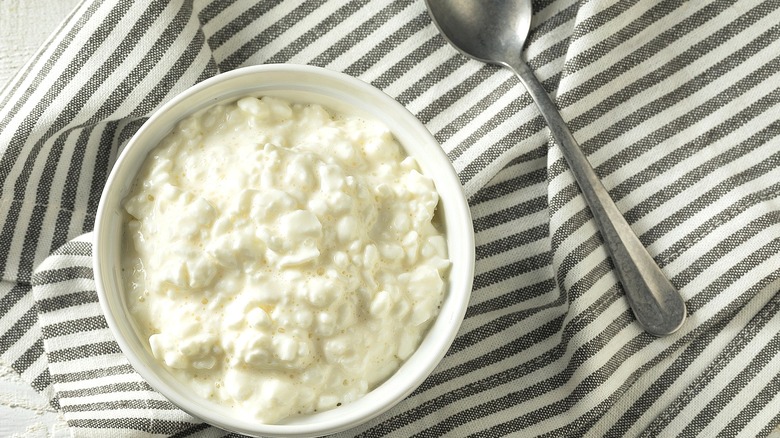 Cottage cheese in white bowl over grey and white striped cloth napkin