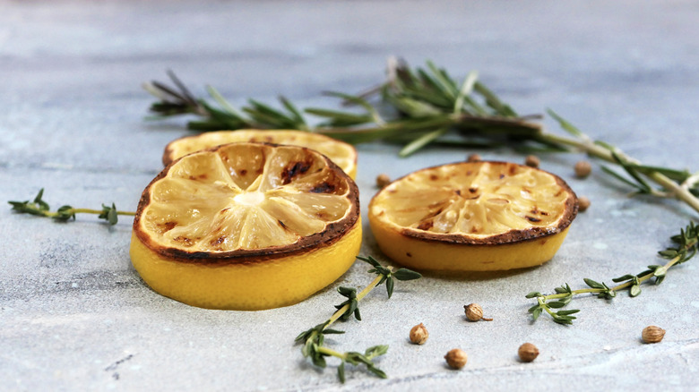 Carred lemon slices and rosemary on gray surface