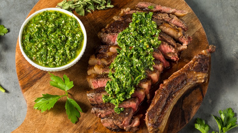 steak with chimichurri sauce on cutting board