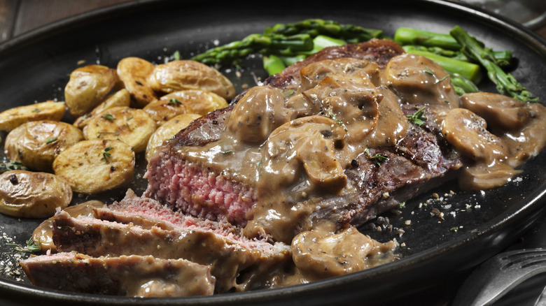 steak with mushroom sauce, roast potatoes, and asparagus
