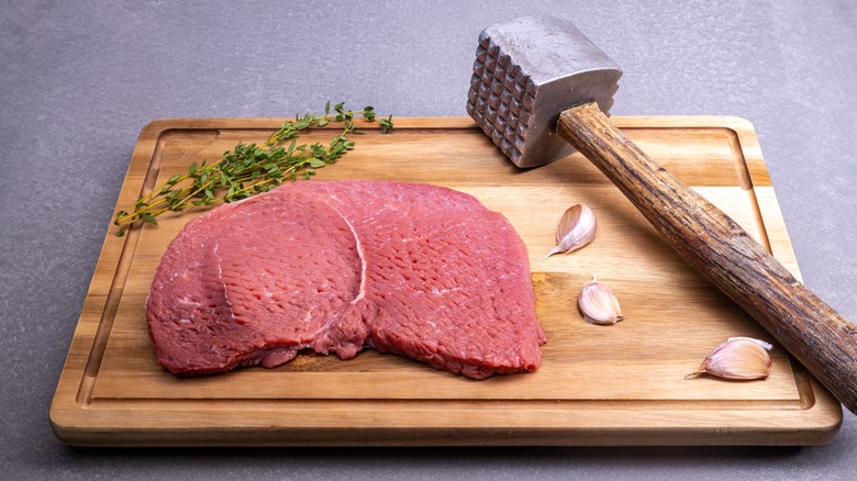 Steak next to tenderizing hammer