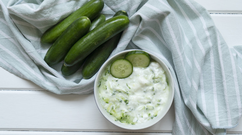 A bowl of tzatziki with cucumbers in the frame.