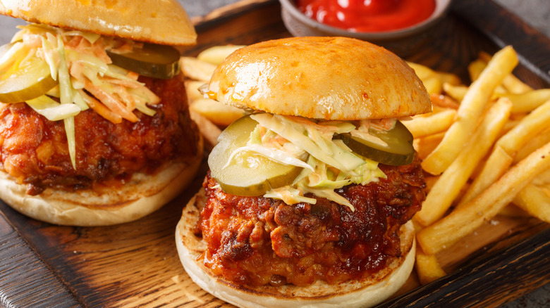 Pickles and slaw on a chicken sandwich beside fries