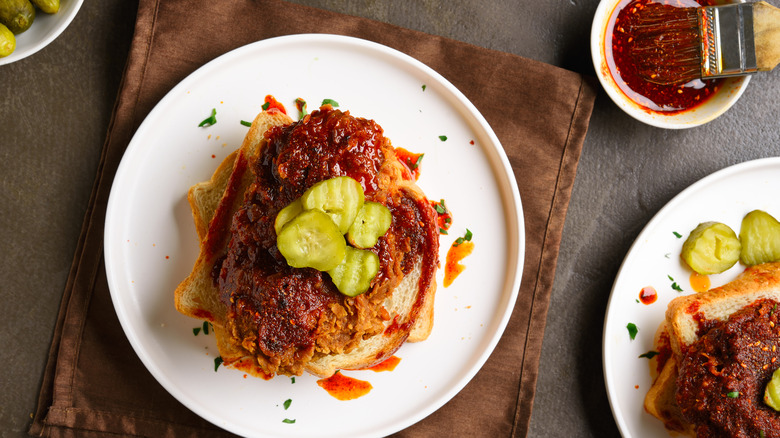 Open-faced Nashville hot chicken sandwich on white plate