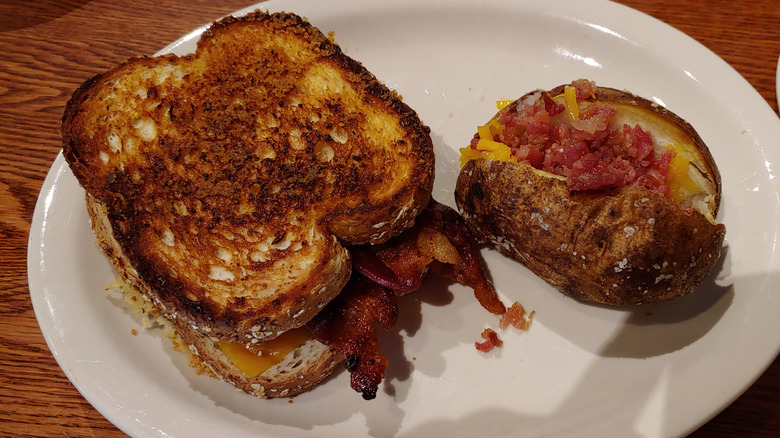 a grilled Cracker Barrel sandwich next to a baked potato