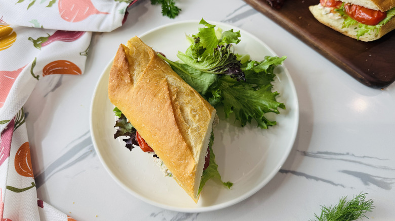 Tuna salad sandwich on a plate with greens on the side