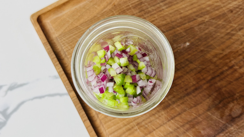 Minced celery and onion in jar on cutting board