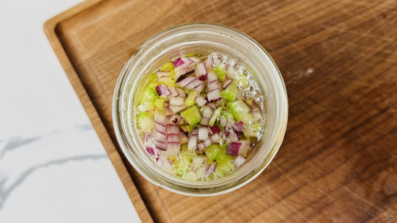 Pickled celery and onion in jar on cutting board
