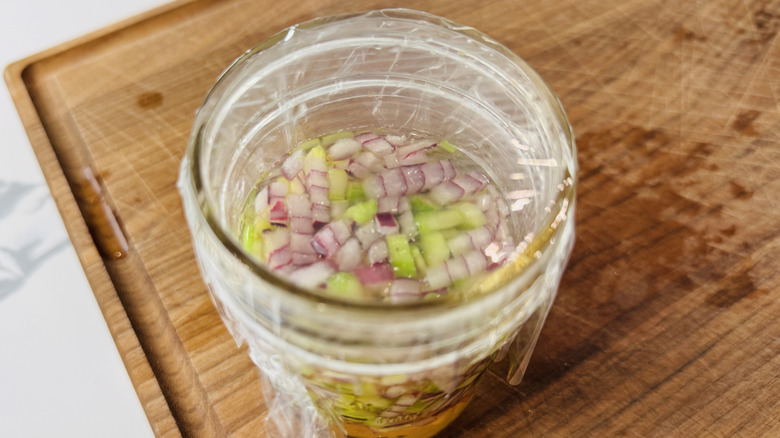 Covered jar of pickled celery and onion on cutting board