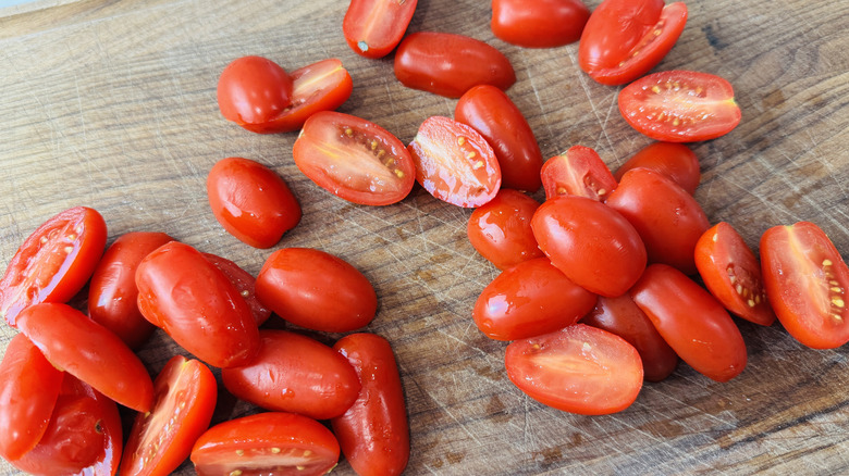 Closeup of halved grape tomatoes on cutting board
