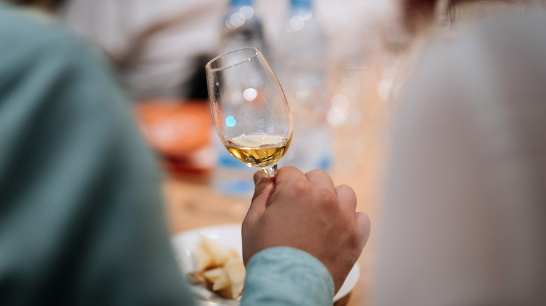 Two people sitting next to each other while one swirls whiskey in a copita glass