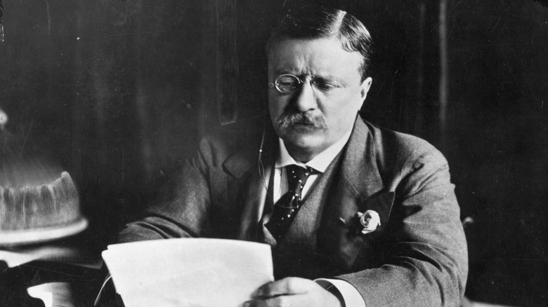 A black and white image of Teddy Roosevelt sitting at a desk.
