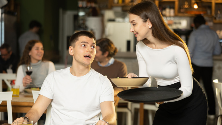 Waitress serving food to a man at a restaurant