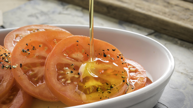 Olive oil being drizzled on tomatoes