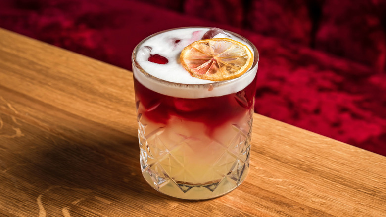 A cocktail in a rocks glass with a red wine float