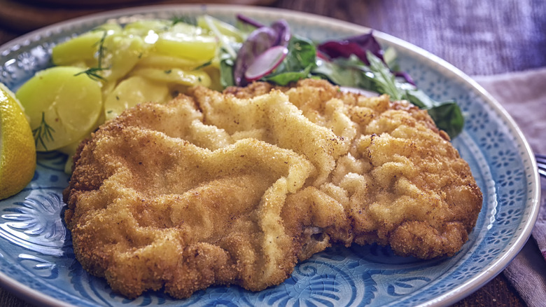 Wiener schnitzel on a blue plate with potatoes and salad