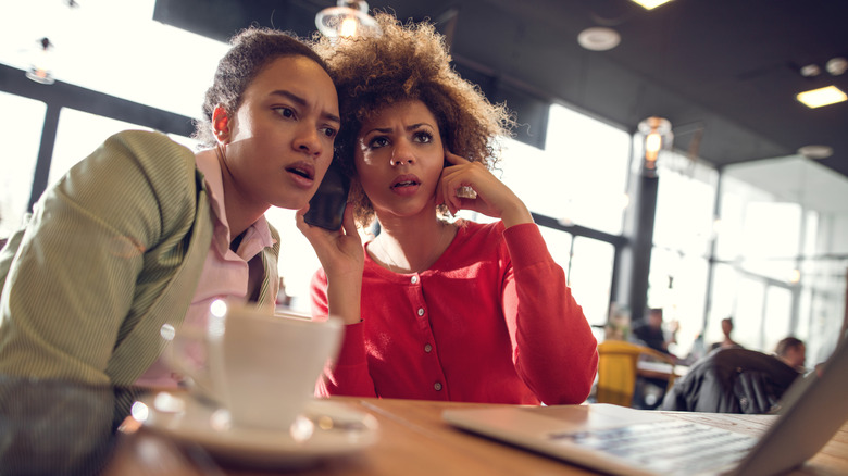 Two people sitting at a table looking shocked