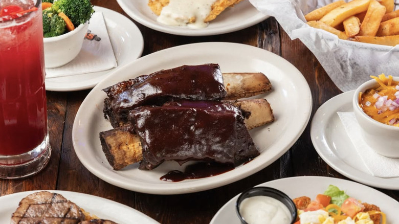 Texas Roadhouse Middle East ribs surrounded by other plates of food and a red drink