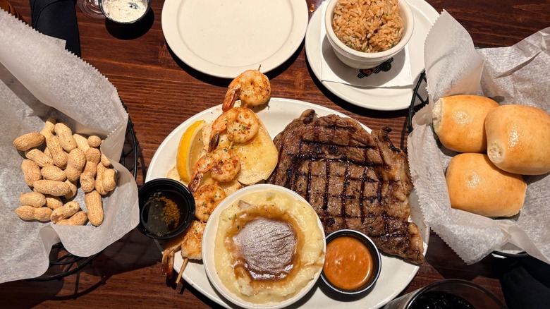 Overhead shot of a meal with steak, shrimp, rice, peanuts, and dinner rolls at Texas Roadhouse