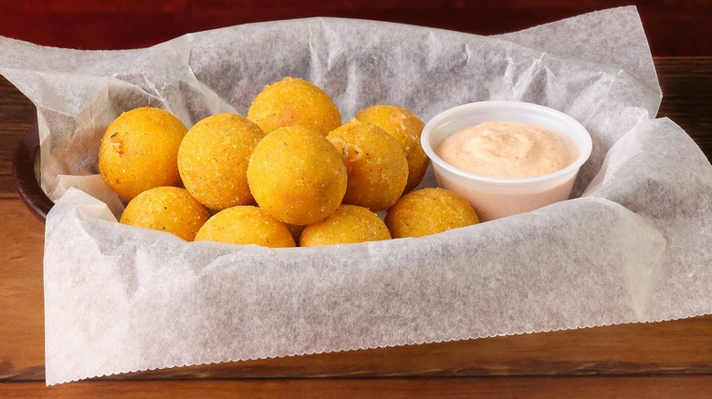 Fried Rattlesnake Bites appetizer in a basket with a side of Cajun sauce