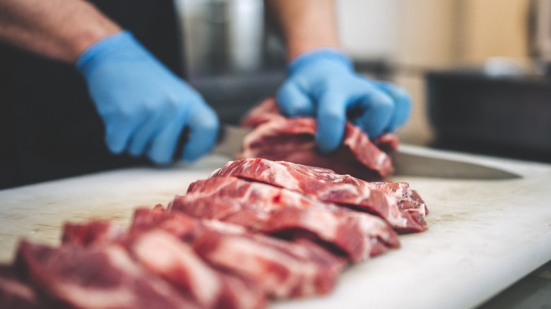 person cutting steaks by hand