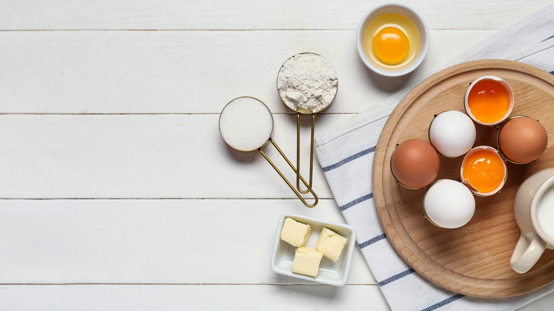 eggs, flour, sugar and butter on a wooden cutting board