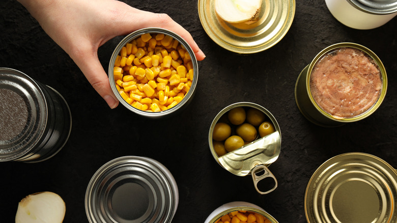 open cans on a table with an arm reaching