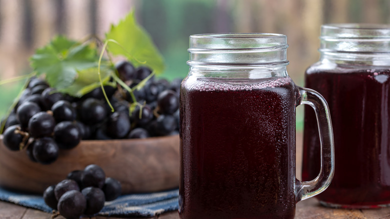 Grape juice in a mason jar with red grapes in the background